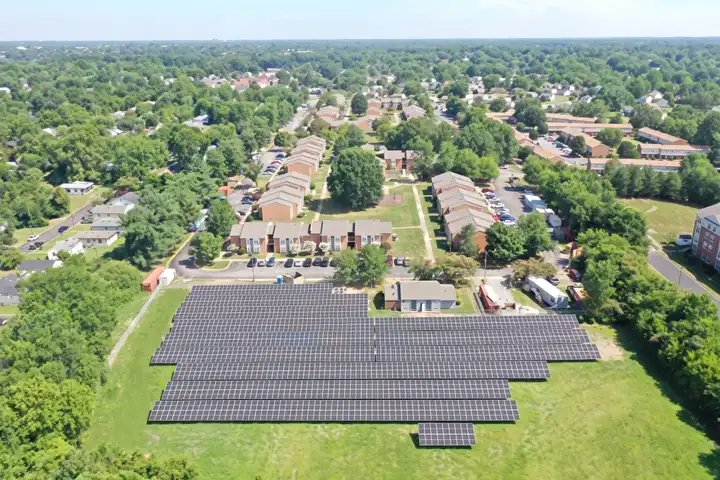 Aerial view of the ground-mounted solar array at Henrico Arms Apartments in Henrico, VA, in a grass field in front of brick apartment buildings